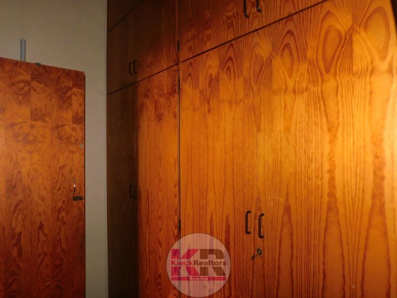 A bedroom interior featuring extensive floor-to-ceiling wooden built-in cupboards providing ample storage space.