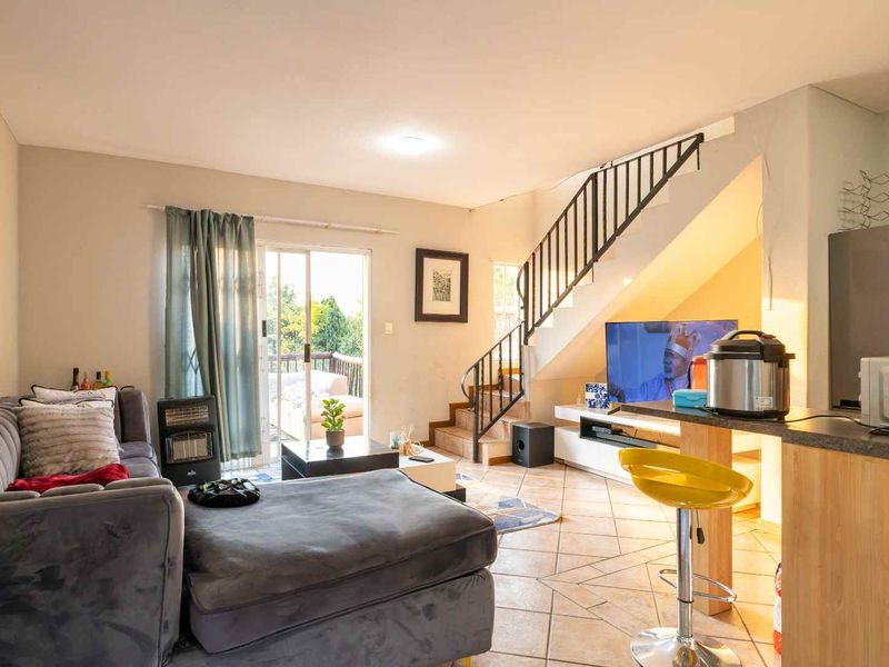 Open-plan living area featuring tiled floors, a staircase with metal balustrade, and a sliding glass door providing access to the outdoor space.