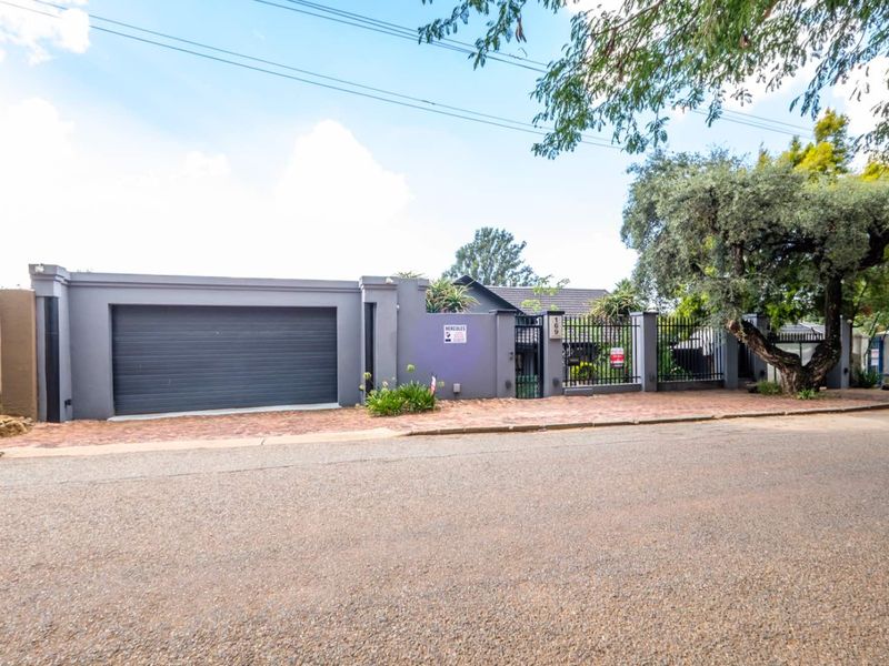Front exterior view of the cottage featuring a secure boundary wall, metal gate, and integrated garage with a paved driveway.