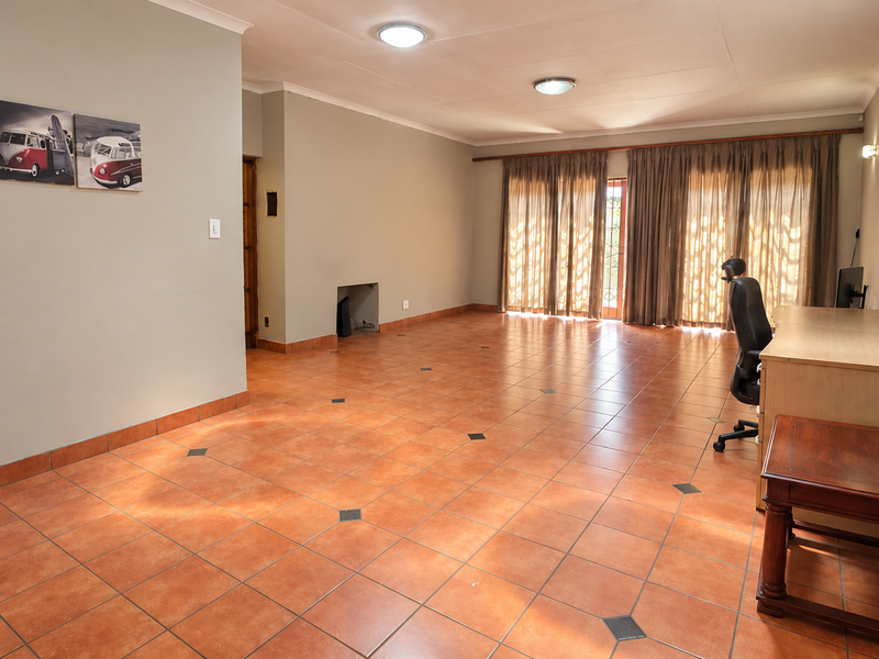 Spacious living area featuring terracotta floor tiles, recessed lighting, and large sliding glass doors that provide ample natural light.