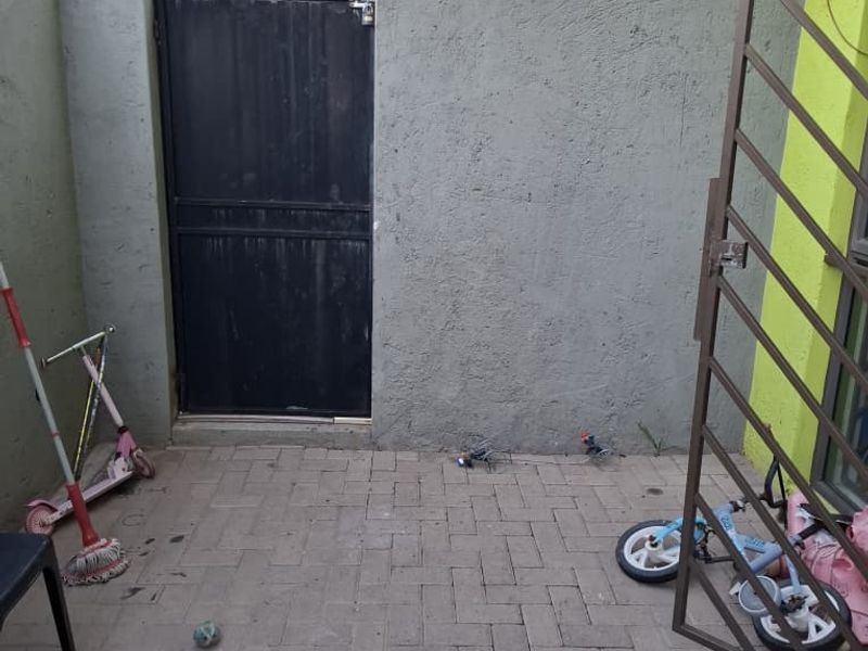 A private paved rear courtyard featuring a secure metal gate and perimeter walling, providing a functional outdoor space for the apartment.