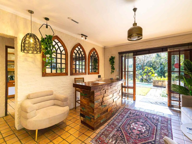 A cozy living area featuring a rustic built-in bar, textured walls, and direct access to the outdoor pool area through timber-framed glass doors.