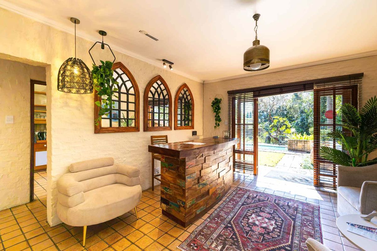 A cozy living area featuring a rustic built-in bar, textured walls, and direct access to the outdoor pool area through timber-framed glass doors.