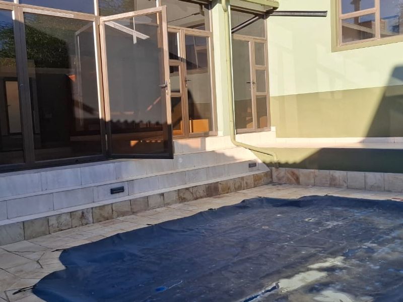Outdoor pool area featuring a tiled patio, recessed lighting, and large aluminium sliding doors providing access to the interior living space.