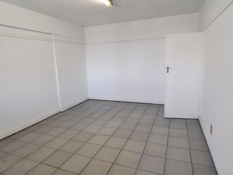 A vacant, neutral office space featuring tiled flooring and clean white walls, suitable for a variety of business or professional uses.