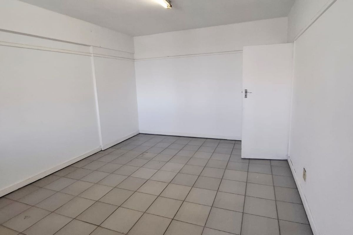 A vacant, neutral office space featuring tiled flooring and clean white walls, suitable for a variety of business or professional uses.
