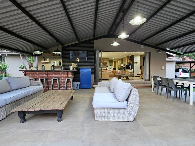 Spacious covered patio featuring a built-in brick bar, tiled flooring, and seamless access to the interior living area through large sliding glass doors.