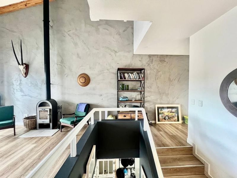 A bright living area featuring a modern freestanding fireplace, textured feature wall, and staircase with white railings, finished with contemporary laminate flooring.