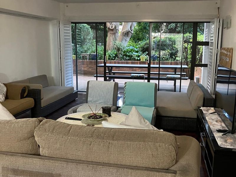 A comfortable living room featuring hardwood flooring and large sliding glass doors that open onto a private patio area.