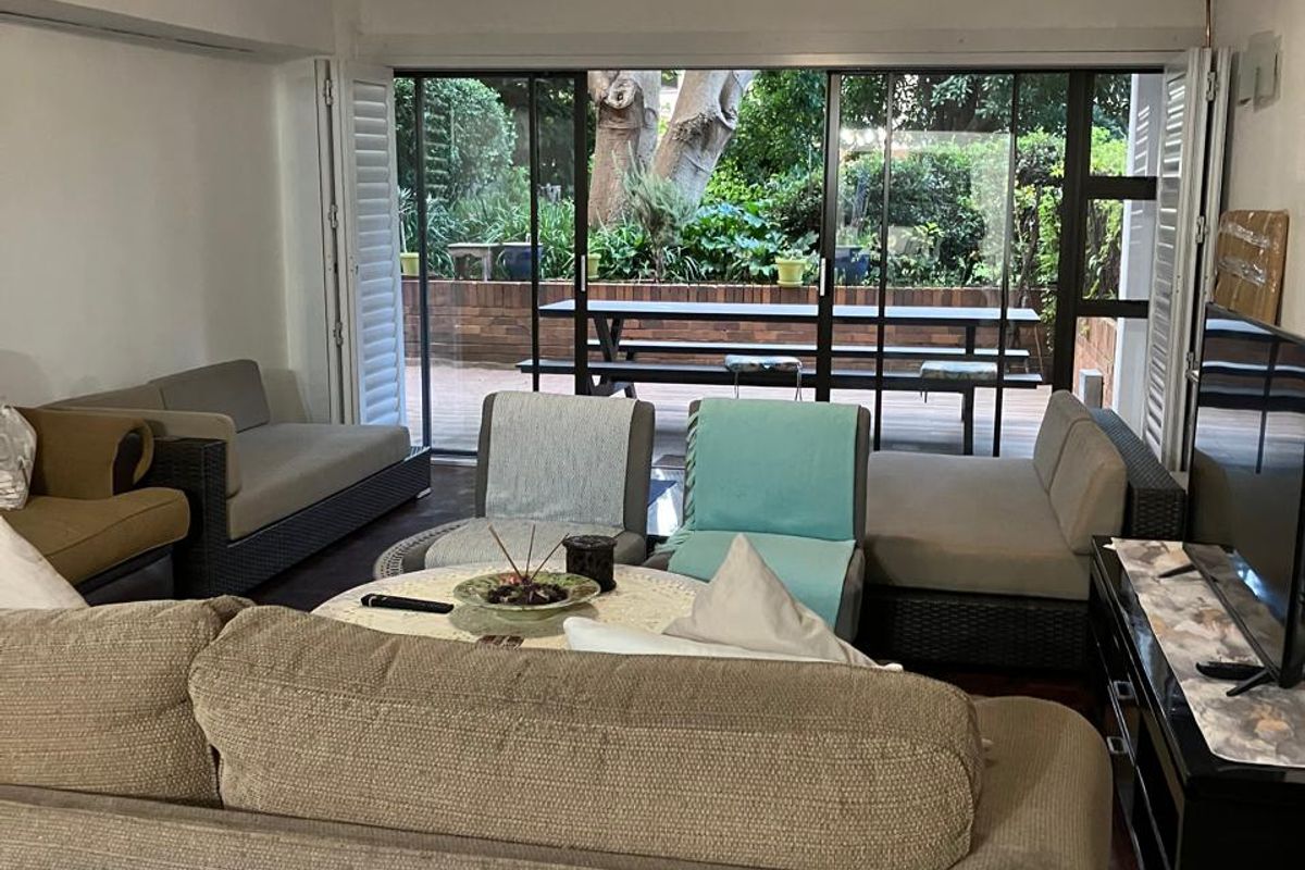A comfortable living room featuring hardwood flooring and large sliding glass doors that open onto a private patio area.