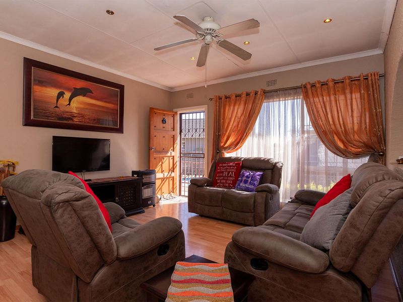 A comfortable living room featuring laminate flooring, a ceiling fan, recessed lighting, and an arched entryway leading to the exterior.
