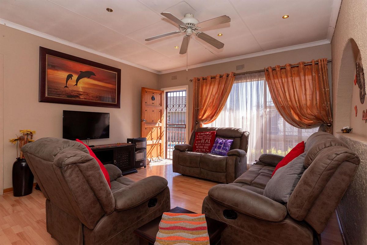 A comfortable living room featuring laminate flooring, a ceiling fan, recessed lighting, and an arched entryway leading to the exterior.