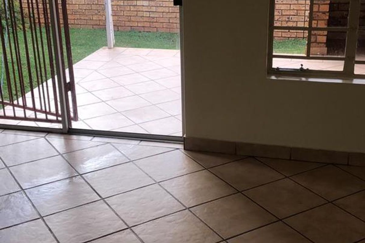 An open-plan living area featuring tiled flooring and a sliding door providing direct access to a private patio and garden area.