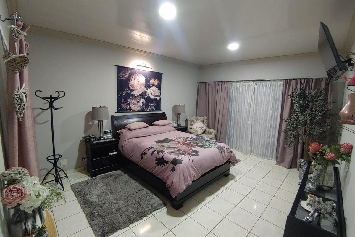 Spacious bedroom featuring tiled flooring, recessed ceiling lighting, and sliding glass doors providing access to the exterior.