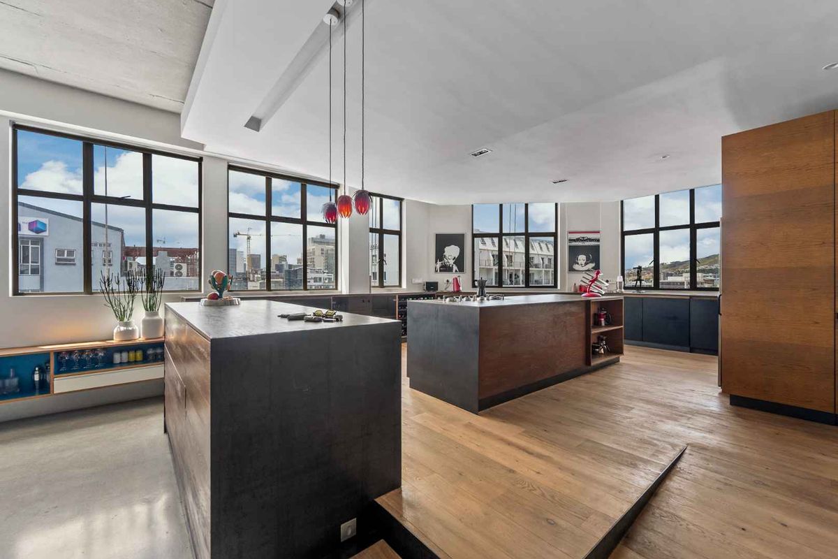 Modern open-plan kitchen featuring dual islands, high-end cabinetry, hardwood flooring, and expansive windows offering panoramic city views.