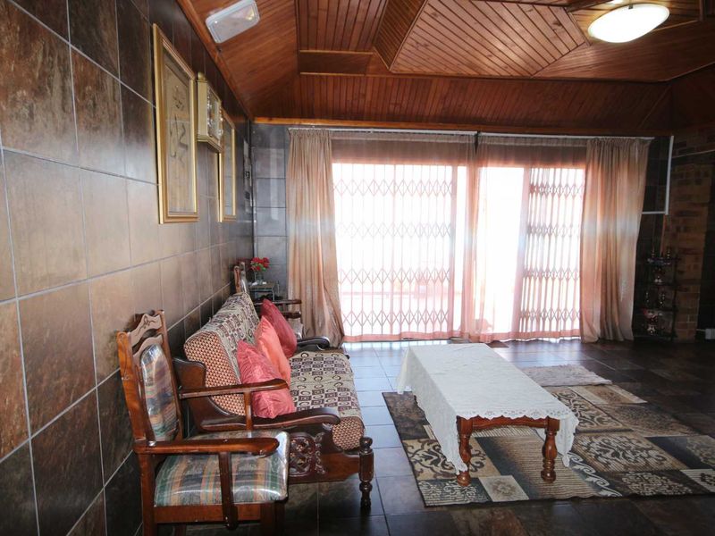 A living room featuring tiled walls, tiled flooring, and a timber panelled ceiling, with sliding glass doors providing access to the exterior.