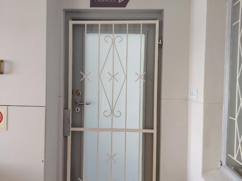 A professional office suite entrance featuring a secure metal security gate and a frosted glass door with business signage.