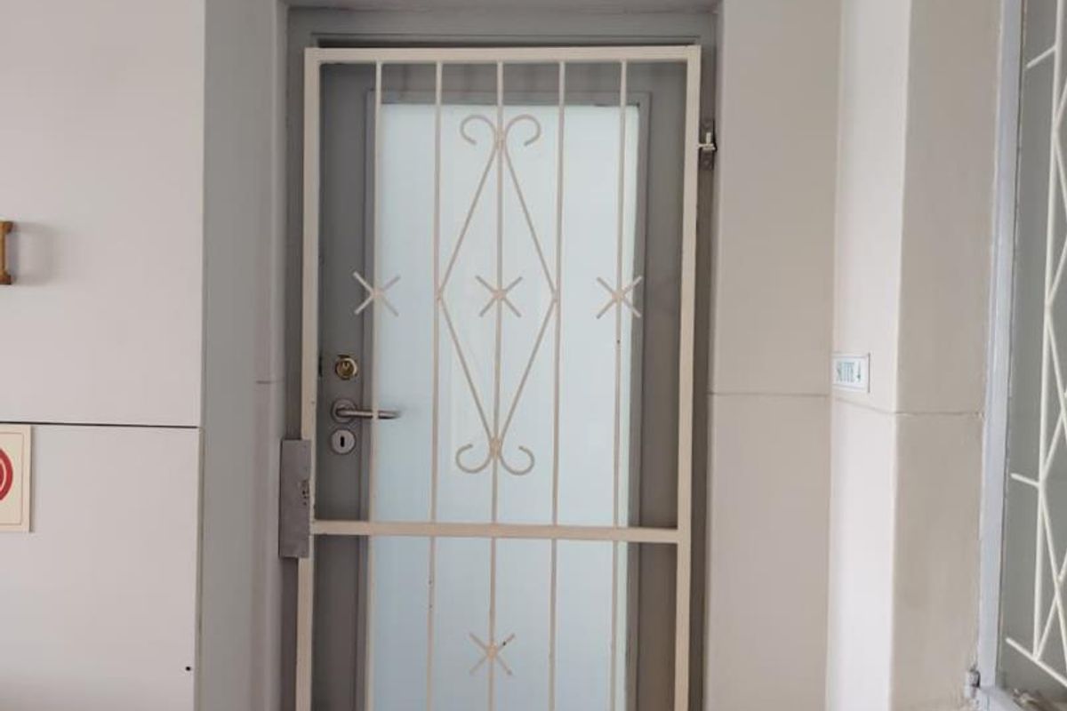 A professional office suite entrance featuring a secure metal security gate and a frosted glass door with business signage.