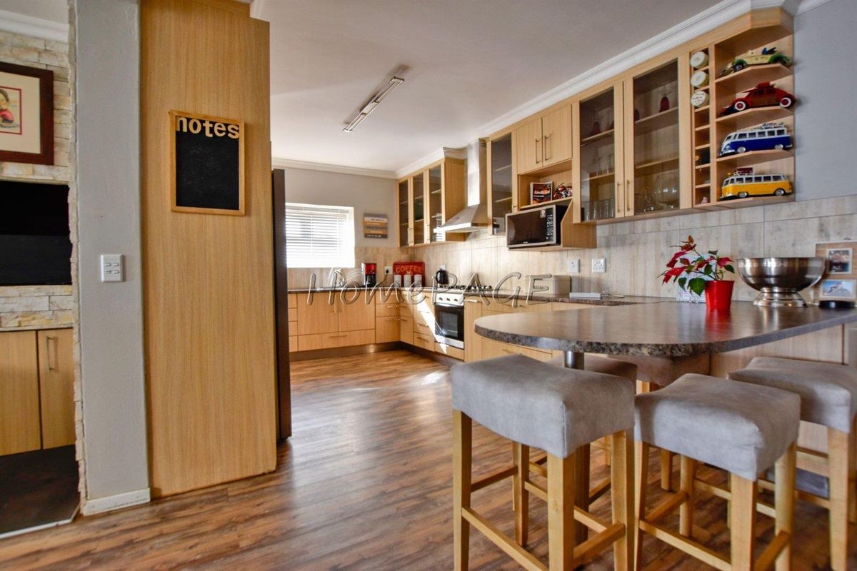 A well-appointed kitchen featuring light wood cabinetry, integrated appliances, a breakfast bar, and wood-look flooring, offering a functional and warm cooking space.