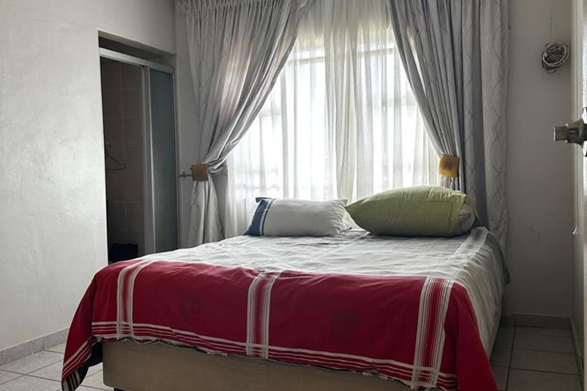 A functional bedroom featuring tiled flooring, a ceiling fan, and an en-suite bathroom access point.