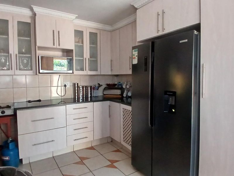 A functional kitchen featuring built-in cabinetry, granite countertops, a gas hob, and a built-in microwave, finished with tiled flooring and crown molding.