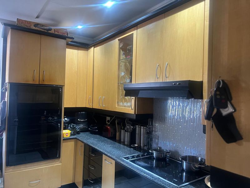 A functional kitchen featuring light wood cabinetry, granite countertops, a built-in oven, and an integrated extractor fan with modern recessed lighting.