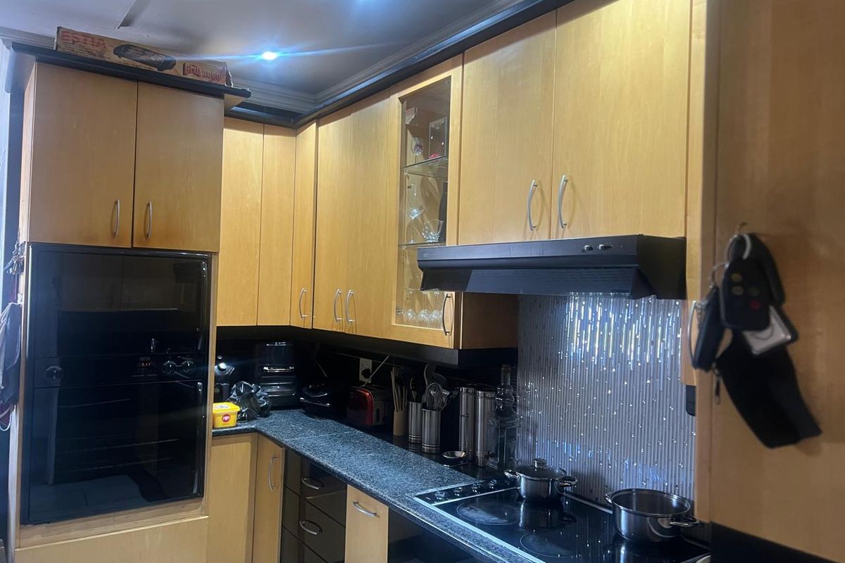 A functional kitchen featuring light wood cabinetry, granite countertops, a built-in oven, and an integrated extractor fan with modern recessed lighting.