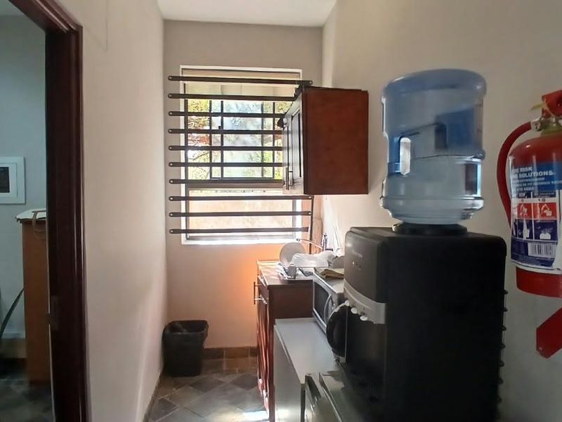 A functional utility space featuring tiled flooring, security bars on the window, and wall-mounted fire safety equipment.