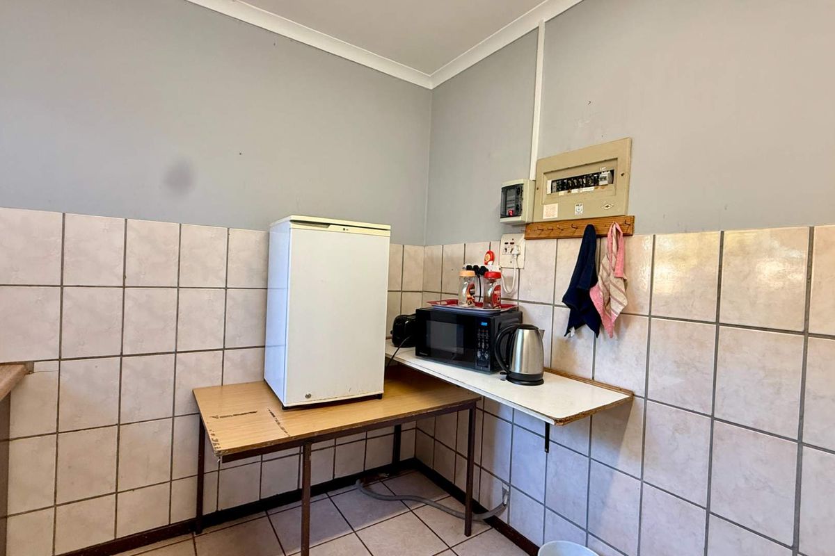 A functional utility or kitchenette area featuring tiled walls, a sink, and an exposed electrical distribution board.