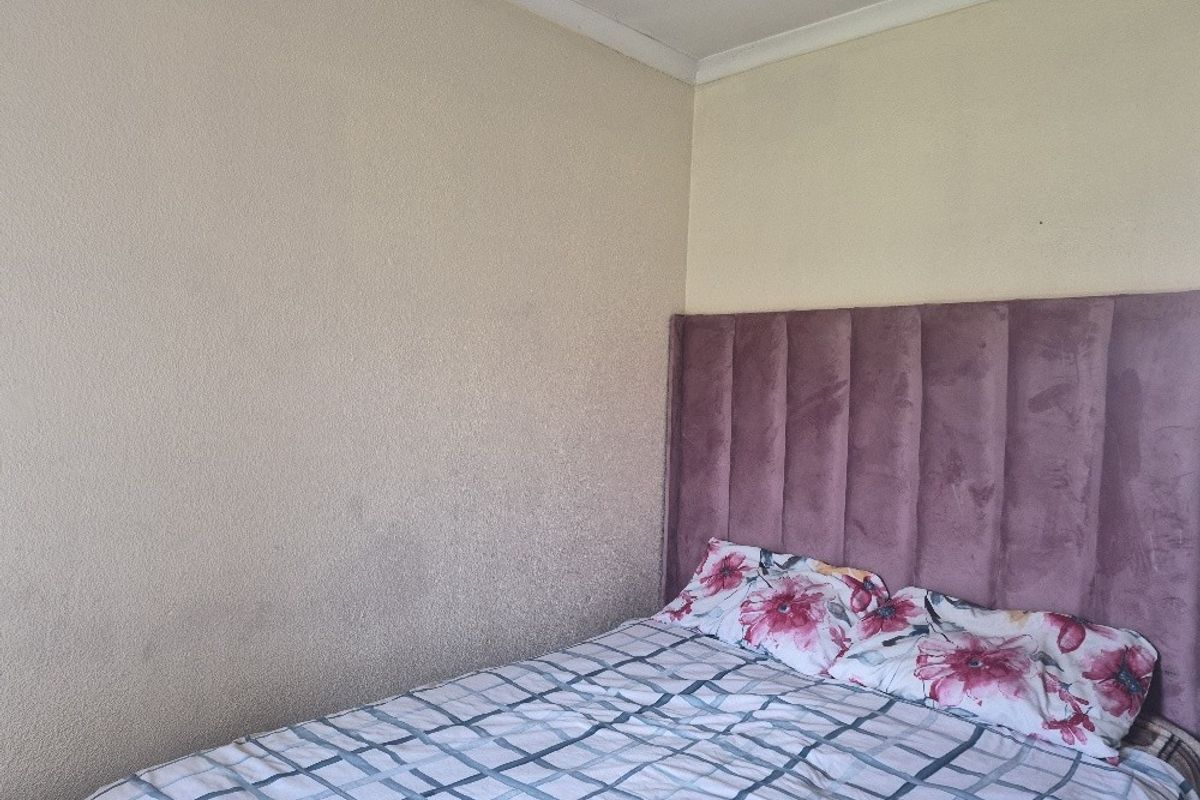 A bedroom interior featuring plain walls and ceiling coving.