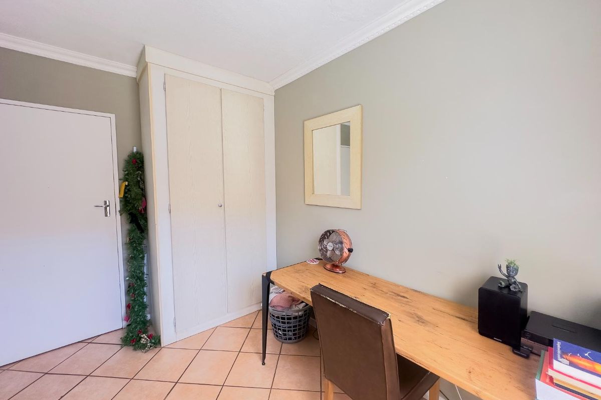 A bedroom featuring ceramic floor tiles, a built-in cupboard, and decorative cornice detailing.