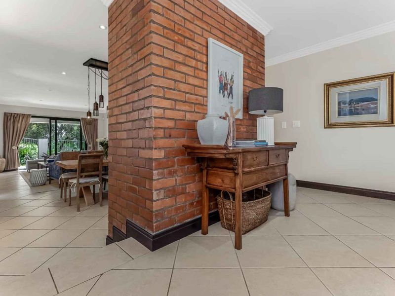 An open-plan living area featuring a prominent exposed brick feature wall, neutral tiled flooring, and sliding glass doors leading to an outdoor space.