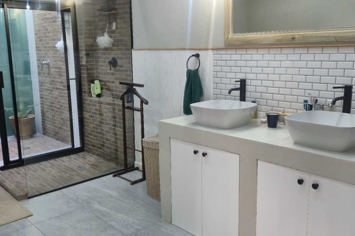 Modern bathroom featuring a double vanity with vessel sinks, subway tile backsplash, and a spacious walk-in shower with glass enclosure.