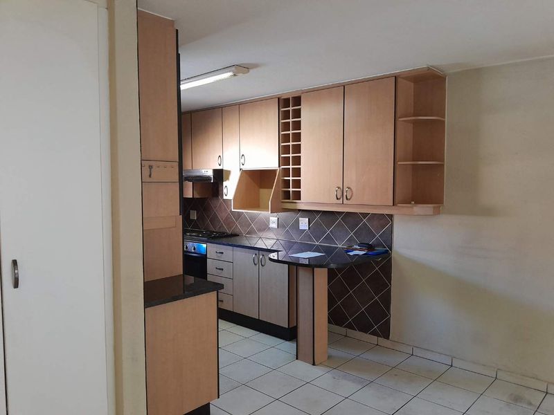 A functional kitchen featuring laminate cabinetry, granite countertops, a built-in oven with extractor fan, and a breakfast bar area.