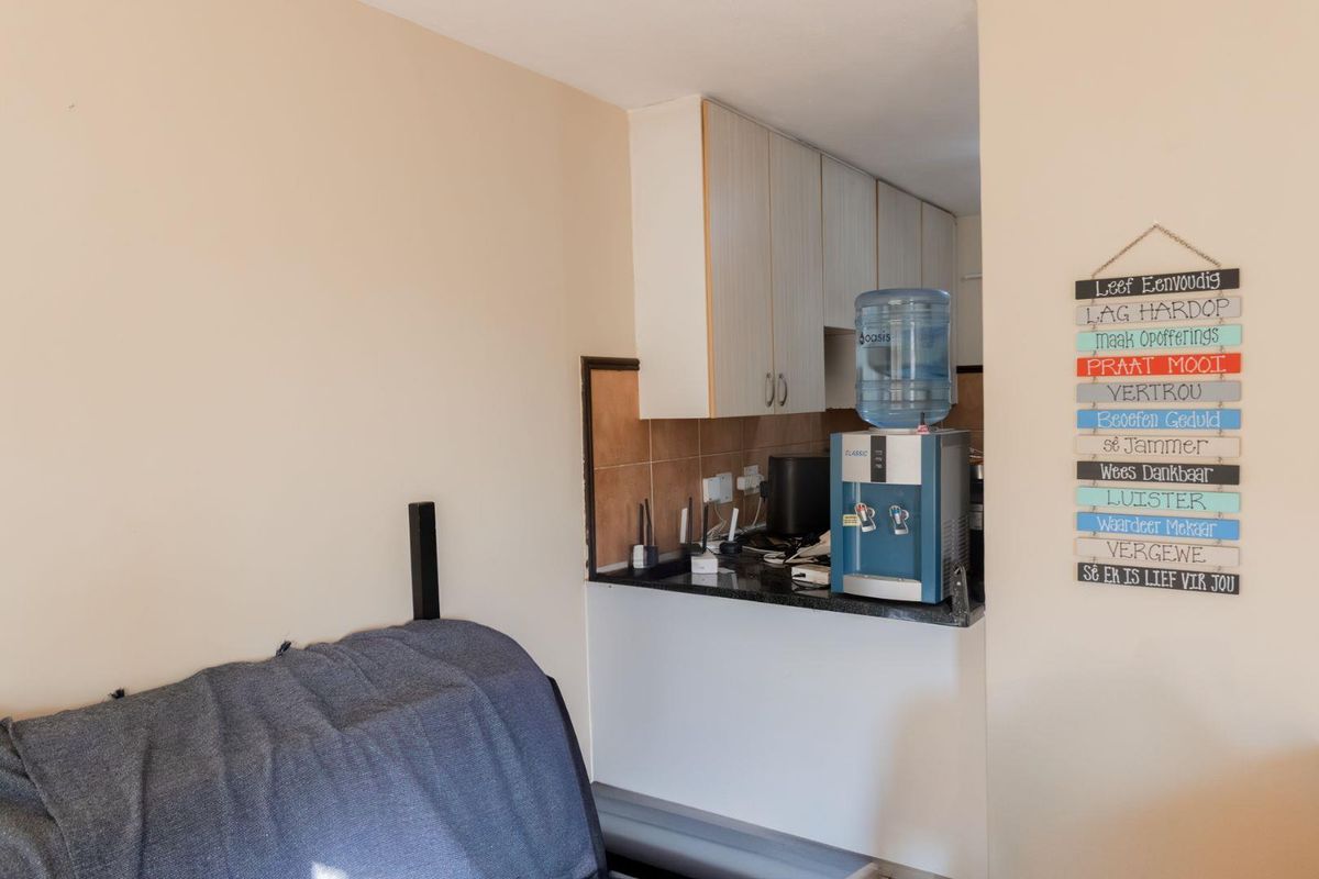 A compact kitchen area featuring built-in cabinetry, a dark stone countertop, and tiled splashback, providing a functional prep space within the apartment.