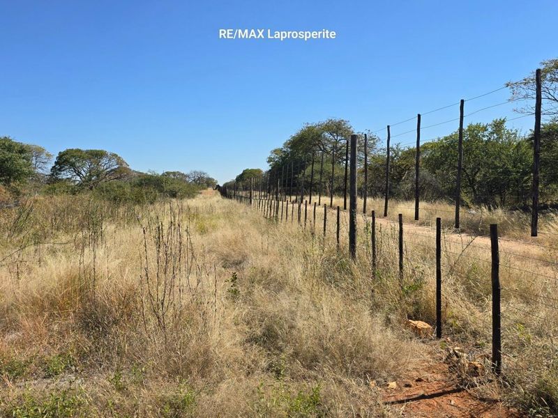 A view of the farm landscape featuring extensive wire fencing and wooden posts along the property boundary.