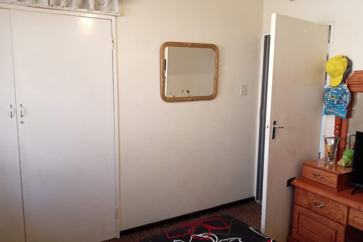 A bedroom featuring built-in cupboards, carpeted flooring, and a standard door entrance.