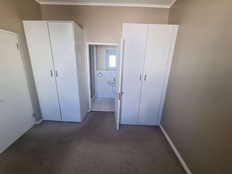 A bedroom featuring built-in cupboards and direct access to an en-suite bathroom, offering a functional layout ready for personalization.