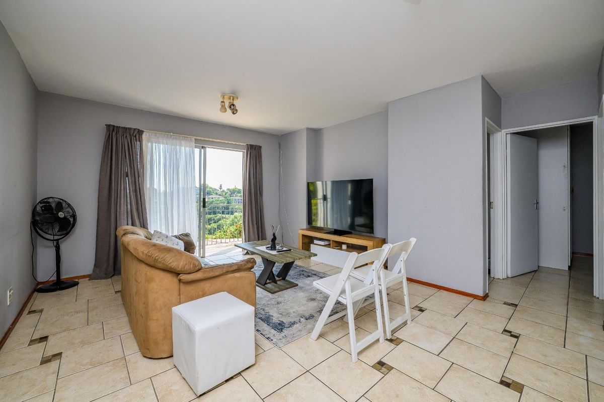 A living room featuring ceramic tile flooring and a sliding glass door that provides access to an outdoor balcony area.