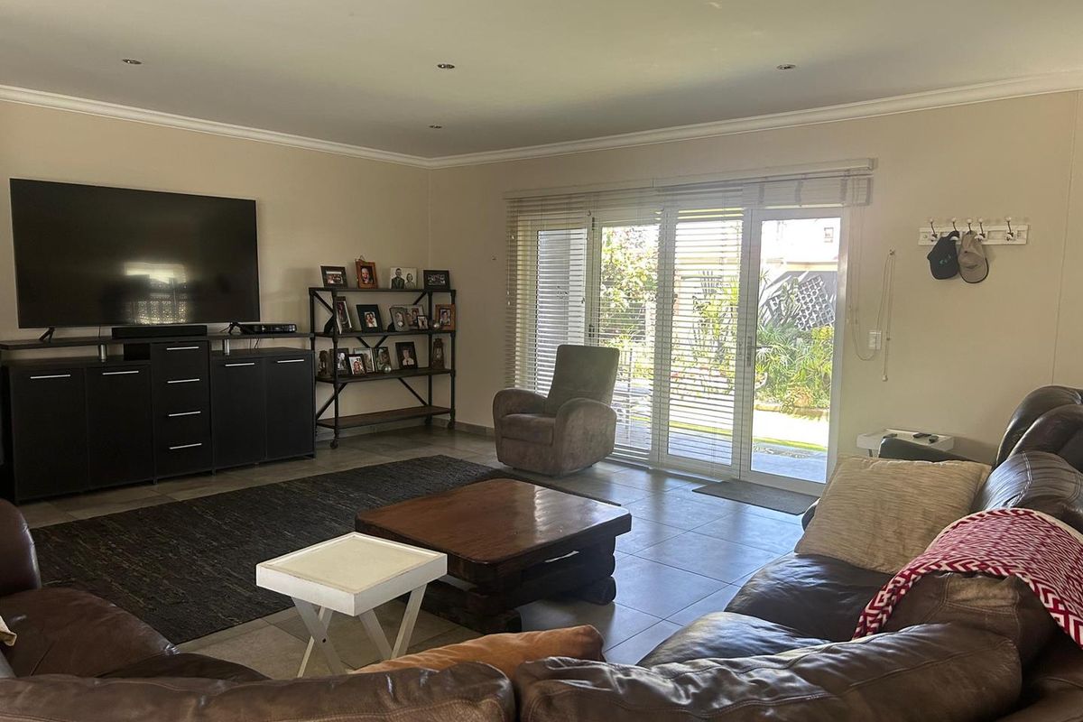 Spacious living room featuring tiled flooring, recessed ceiling lighting, and large sliding glass doors providing direct access to the rear garden area.
