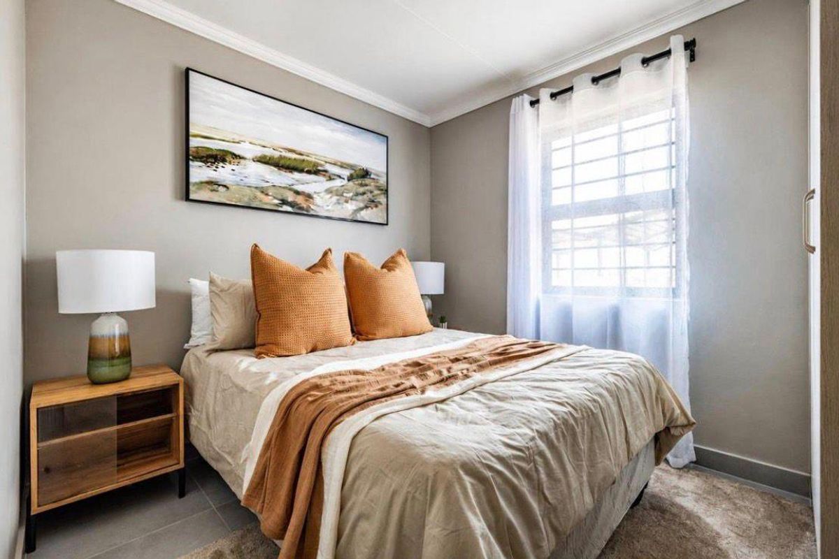A well-maintained bedroom featuring neutral wall tones, crown molding, a window with security bars, and built-in cabinetry.