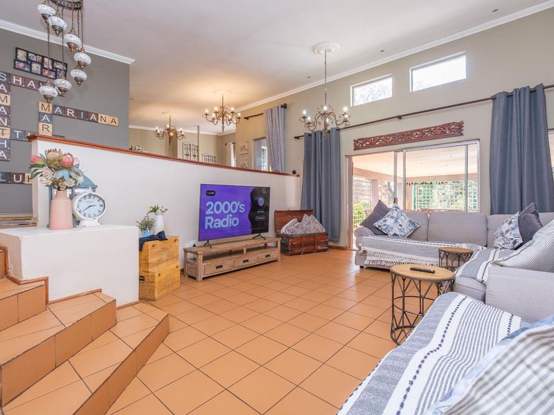 Spacious split-level living room featuring tiled flooring, high ceilings with decorative roses, and large sliding doors providing access to the outdoor area.