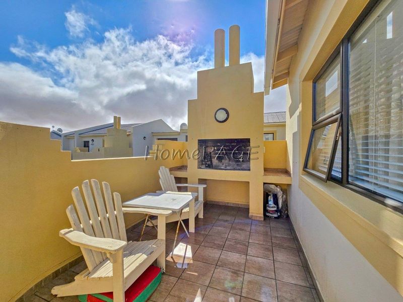 Covered patio area featuring a built-in braai and tiled flooring, providing a functional outdoor entertainment space.