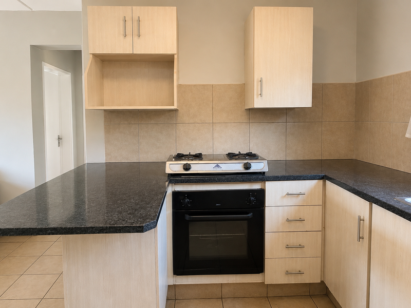 A functional kitchen featuring light wood cabinetry, dark granite countertops, a built-in oven with gas hob, and neutral tiled backsplash.