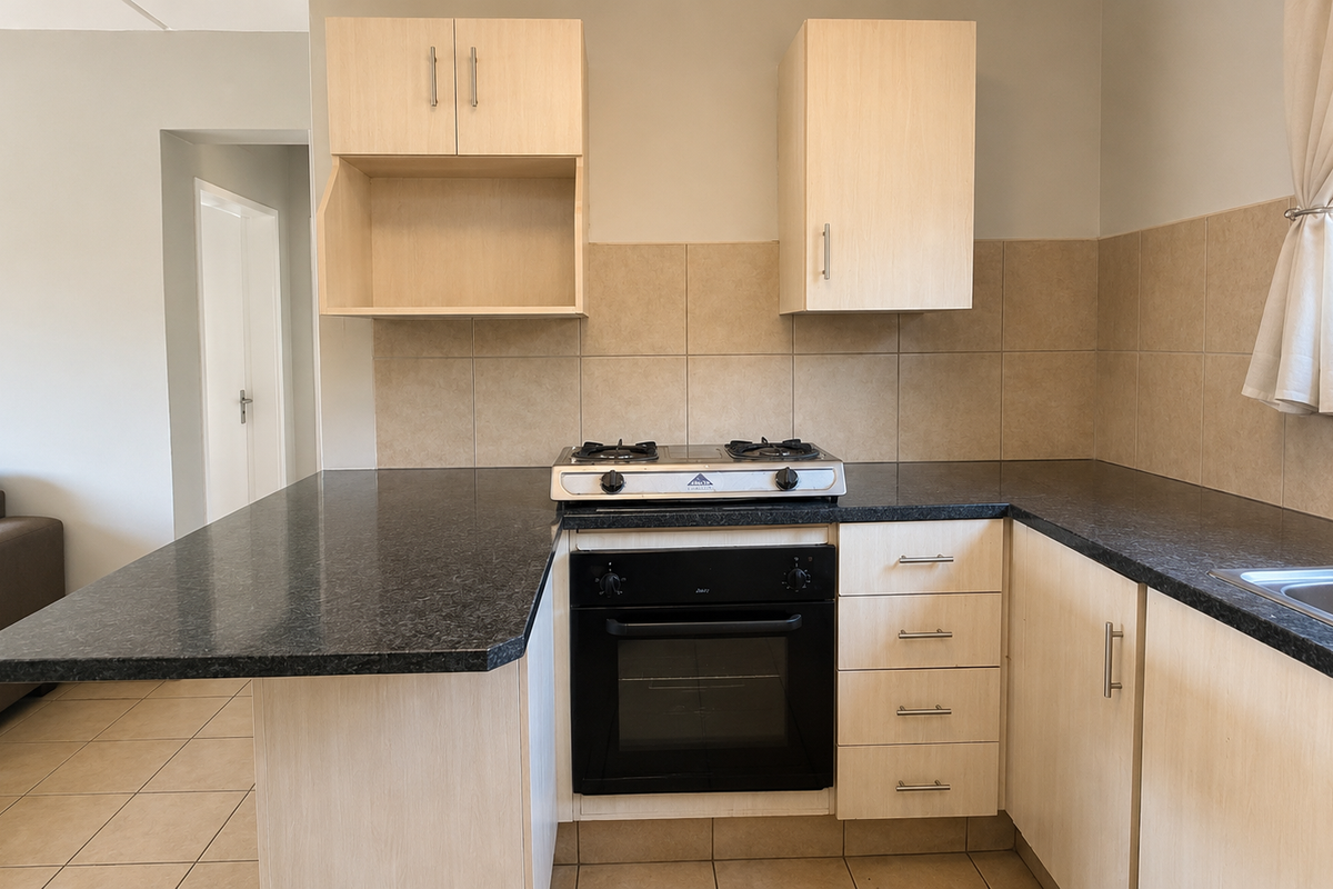A functional kitchen featuring light wood cabinetry, dark granite countertops, a built-in oven with gas hob, and neutral tiled backsplash.