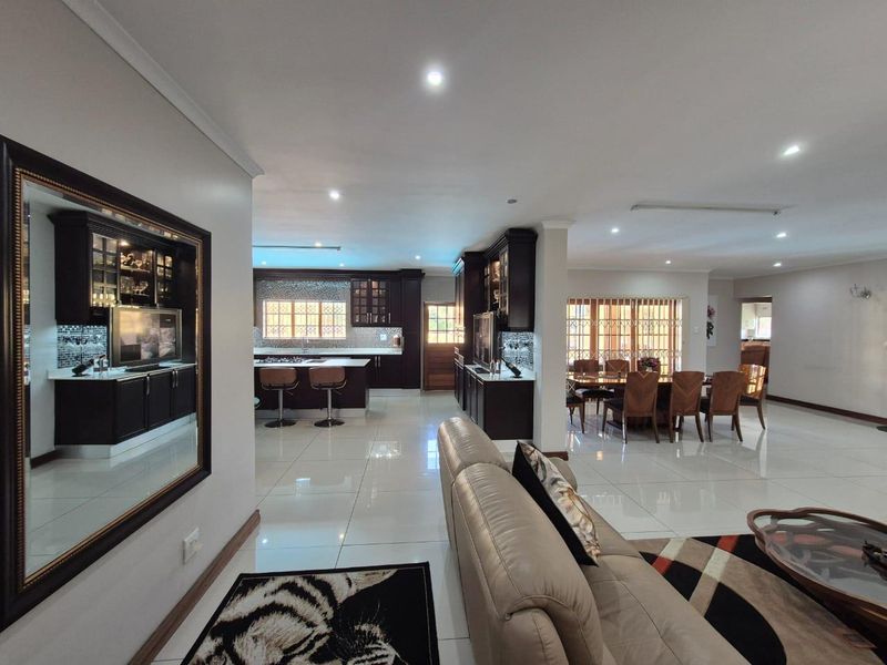 Spacious open-plan living area featuring a modern kitchen with dark cabinetry, a central island, and polished porcelain floor tiles throughout.