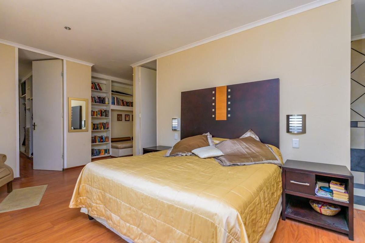 Spacious bedroom featuring laminate flooring, built-in shelving, and an integrated wardrobe, offering a functional layout with neutral wall finishes.