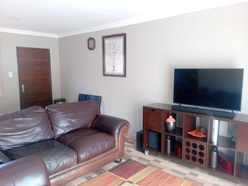 A living room featuring tiled flooring, neutral wall paint, and a solid wooden door.