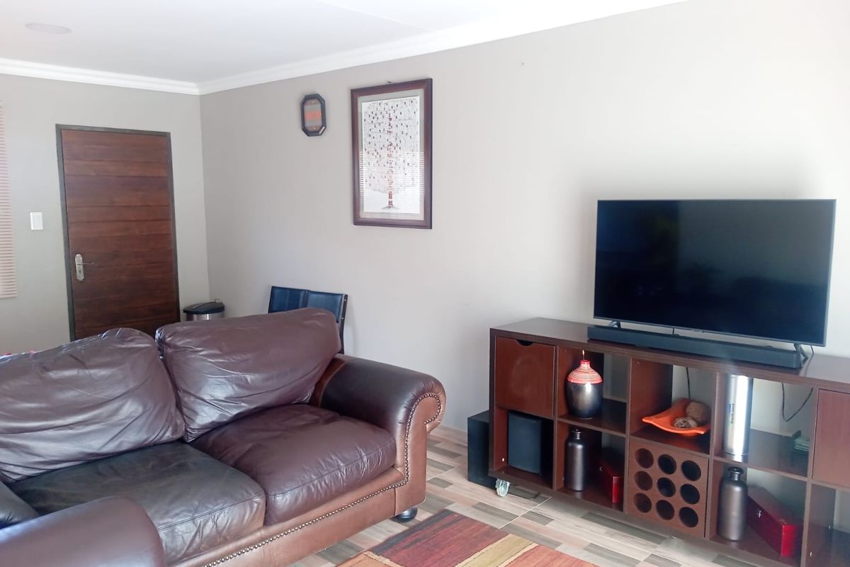 A living room featuring tiled flooring, neutral wall paint, and a solid wooden door.