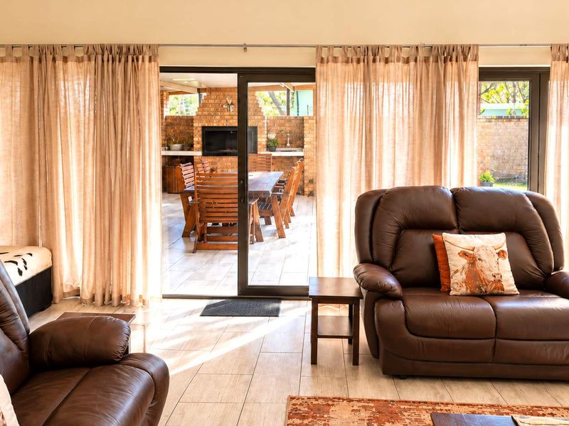 Spacious living room featuring large sliding glass doors that provide seamless access to an outdoor patio area, finished with neutral tiled flooring.